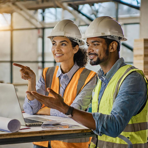 Construction manager at the desk using a laptop with Vitlous software: calendar view, resource allocation chart, and completed tasks checklist.